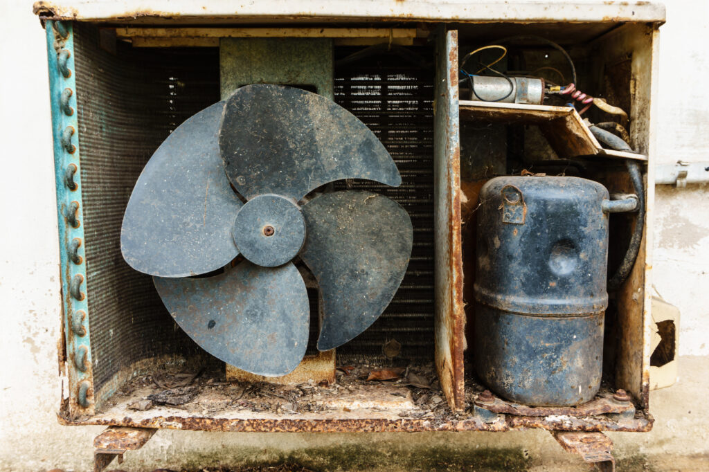 A picture of the internals of an old, worn, rusty, and dirty air conditioning unit in need of replacement